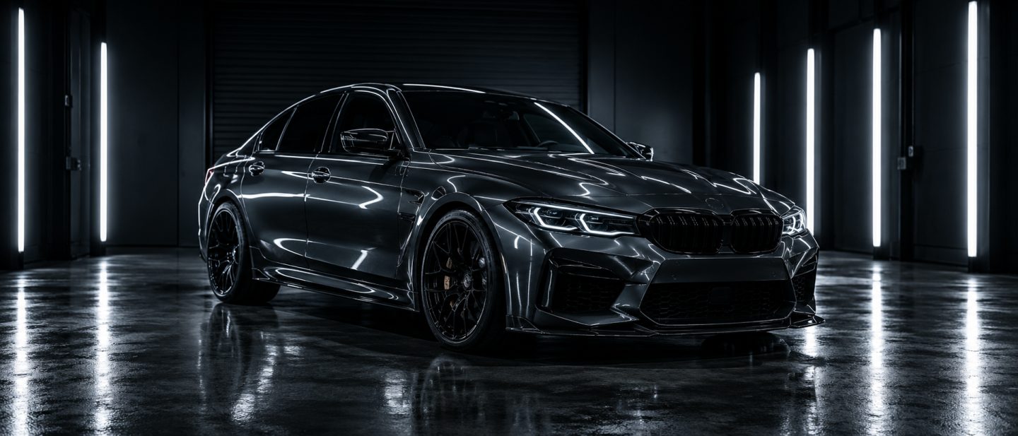 A dark grey sports sedan under workshop lighting